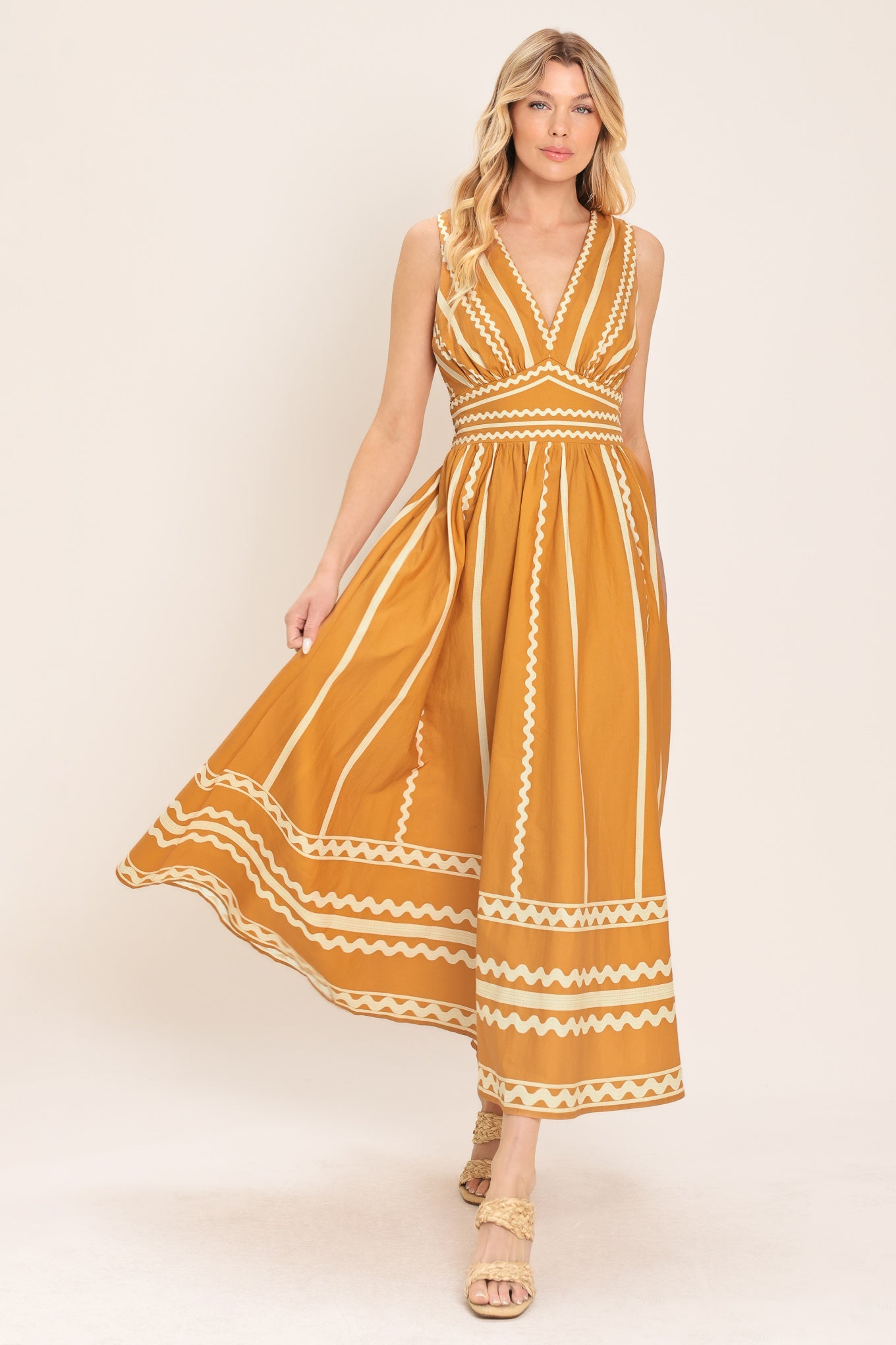 Woman wearing a mustard yellow dress with white patterns on a beige background